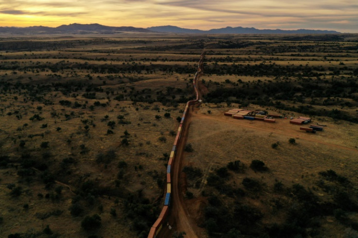 Desde el aire, la pared improvisada de contenedores de envío a lo largo de la frontera entre Estados Unidos y México en Arizona se asemeja a un enorme tren de carga estacionario.