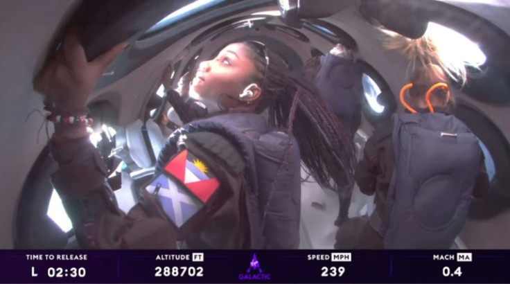 Anastatia Mayers (frente a la izquierda), Jon Goodwin (atrás a la derecha) y la instructora jefe de astronautas Beth Moses (frente a la derecha) miran por las ventanas del espacio a bordo de la nave espacial Virgin Galactic