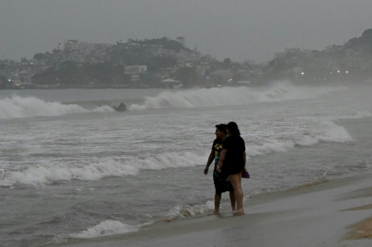 Los bañistas miran al mar mientras el huracán Otis se acerca al centro turístico mexicano de Acapulco.